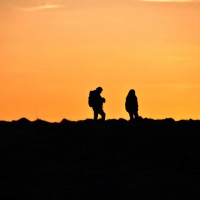 Two people walking under the midnight sun in Eggum, Lofoten, Norway